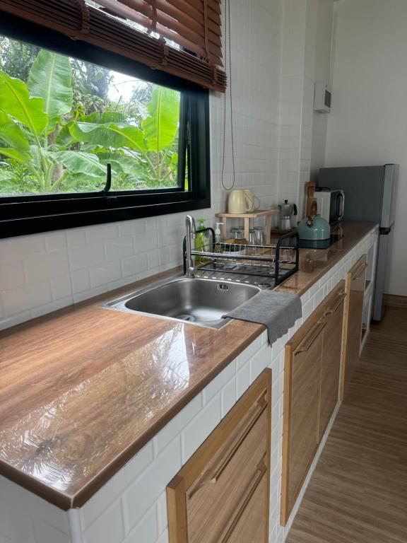 a kitchen counter with a sink and a window at Chaota Modern House in Ban Ao Makham