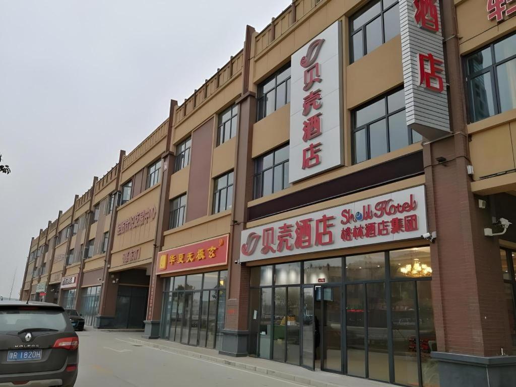 a building with signs on the side of a street at Shell Hotel Nanyang High-Speed Railway Station Jiangying Airport Huayaocheng in Nanyang