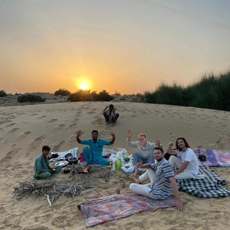 a group of people sitting in the sand on the beach at Hostel Camel Castle & Safari in Jaisalmer