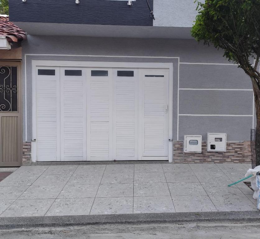 une porte de garage blanche sur le côté de la maison dans l'établissement Hermosa casa en Cartago V, à Cartago