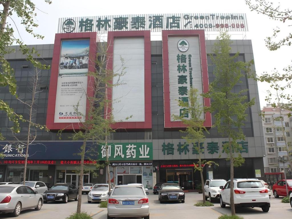 a building with cars parked in a parking lot at GreenTree Inn Jining Yanzhou Jiuzhou Fangyuan Business Hotel in Jining