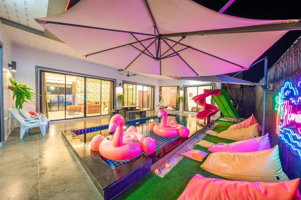 a room with a pool with pink inflatable flamingos at Flamingo Na Jomtien in Na Jomtien