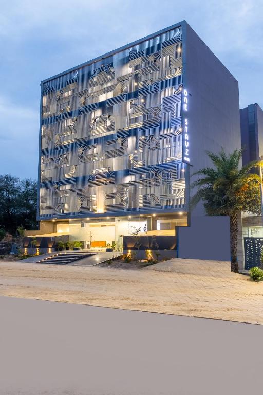 a large glass building with a palm tree in front of it at One Stayz, sector 70A, Gurugram near Sohna Road in Gurgaon