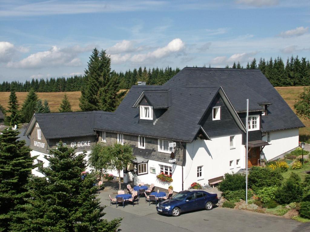 ein großes weißes Haus mit schwarzem Dach in der Unterkunft Berggasthof zur Glocke in Winterberg