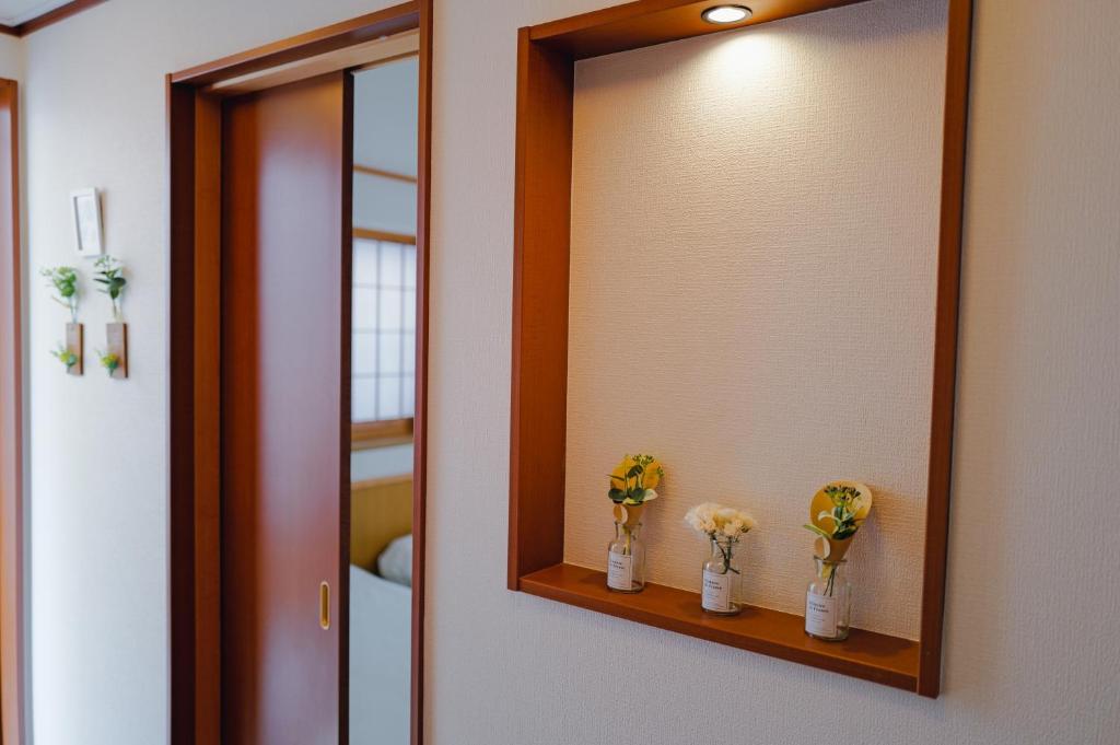 a bathroom mirror with three vases with flowers on it at Akira Hiro House - Room201 in Tokyo