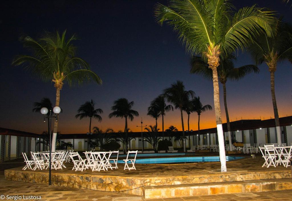un grupo de sillas y palmeras junto a una piscina en Fiesta Bahiana Club Hotel, en Irecê
