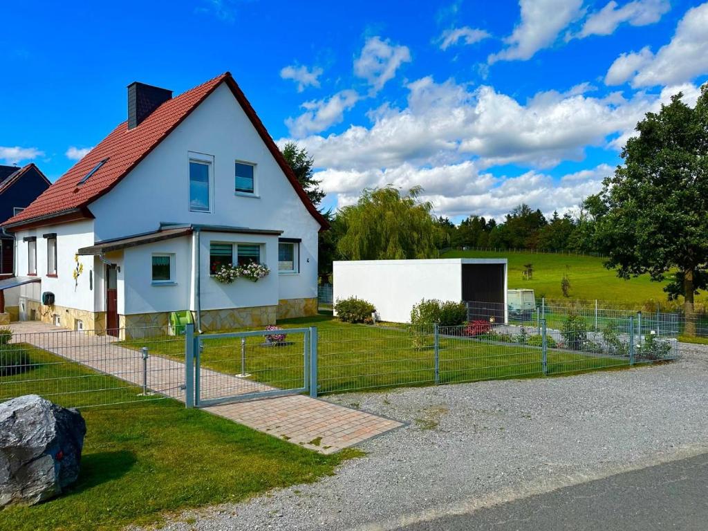 a white house with a fence around it at Ferienhaus Wiesenblick in Hüttenrode