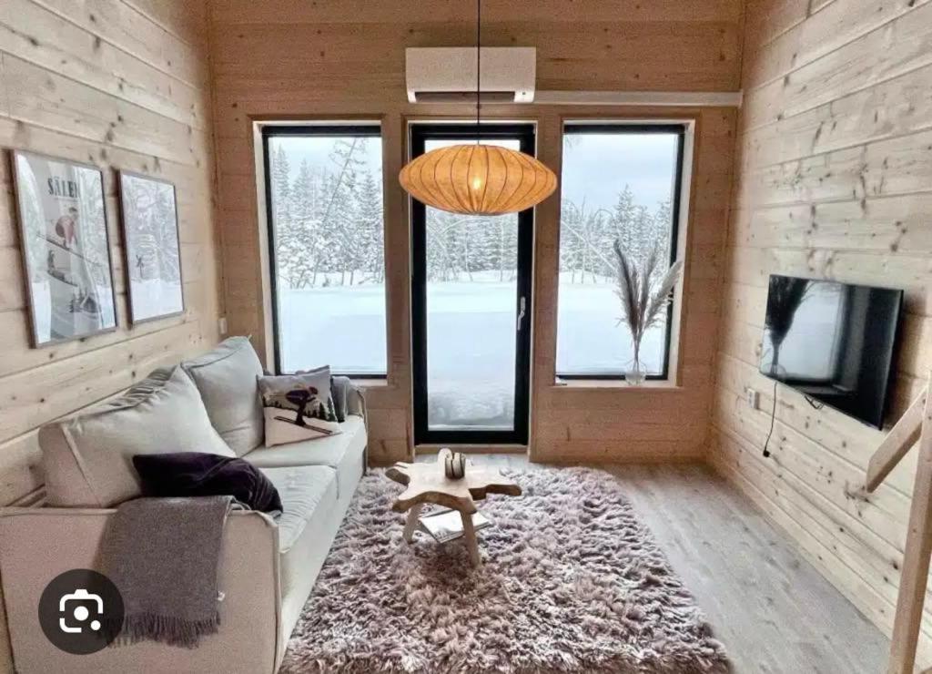 Una sala de estar con un sofá y un televisor y ventanas. en Lindvallen - Modern Mountain House, en Sälen