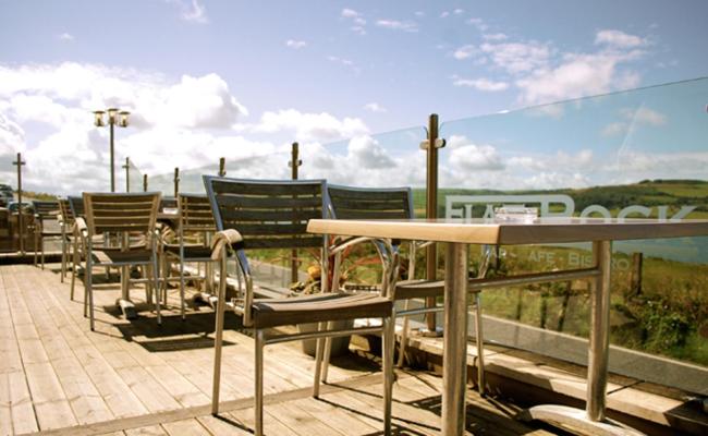 - un ensemble de chaises et d'une table sur une terrasse dans l'établissement Gwbert Hotel, à Cardigan