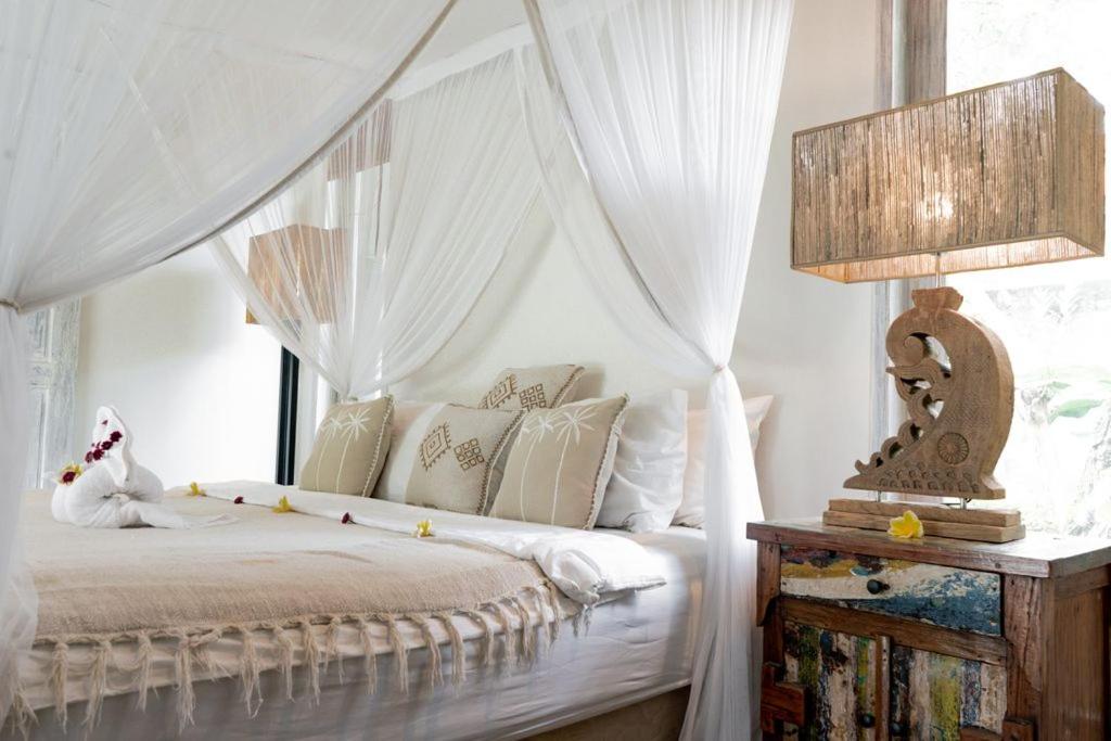 a bedroom with a canopy bed with white curtains at Villa Fleur in Tumbak Bayuh