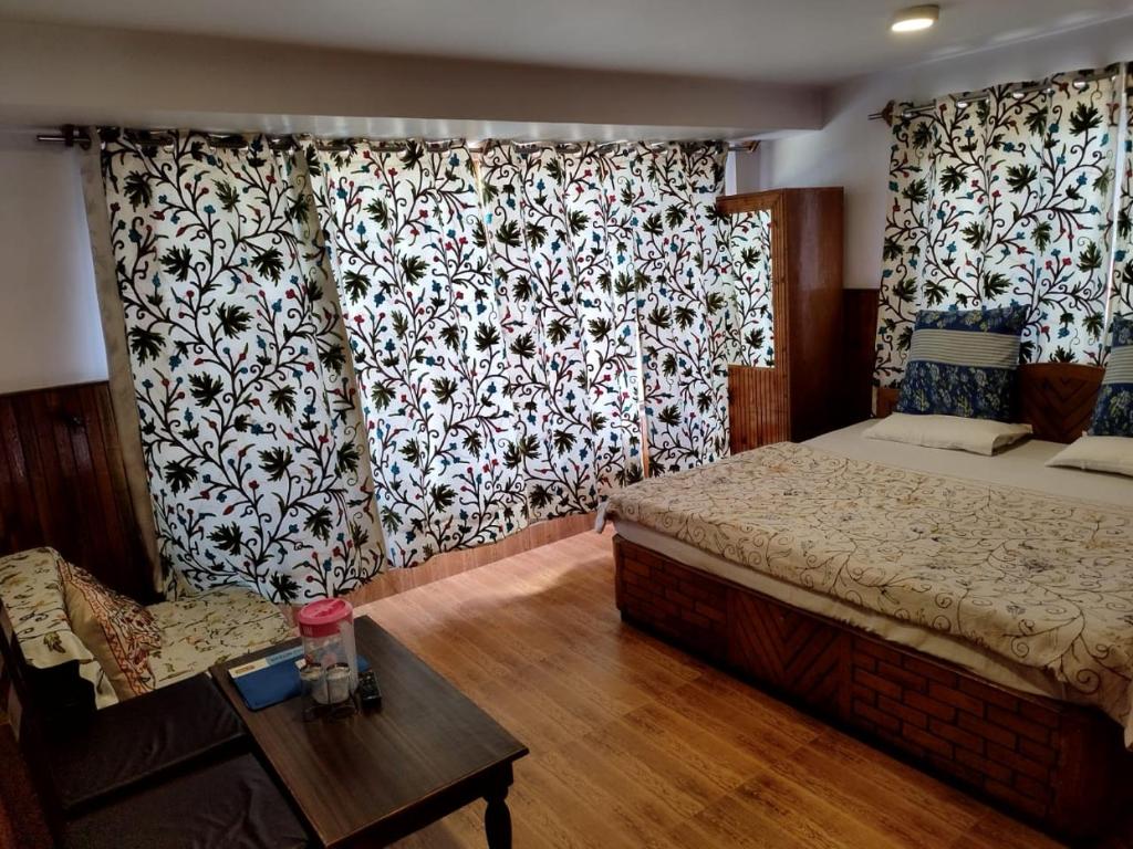 a bedroom with a bed and a table and curtains at Hotel Palestine in Pahalgām