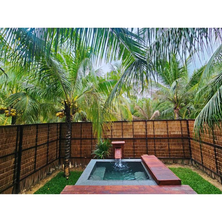 a small fountain in a yard with a fence at Cheewatra Farmstay Coconut House in Ban Tha Maphrao