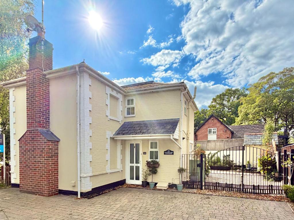 ein weißes Haus mit einem gemauerten Kamin in der Unterkunft Gateman's Cottage - Three Bedroom Detached Home - Free Parking - Close to New Forest and Beaches in West Moors