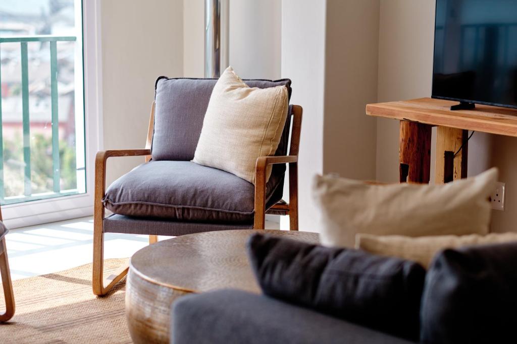 sala de estar con sofá, silla y TV en Seaview Haven - Luxury Coastal Escape Simon's Town, en Simonʼs Town