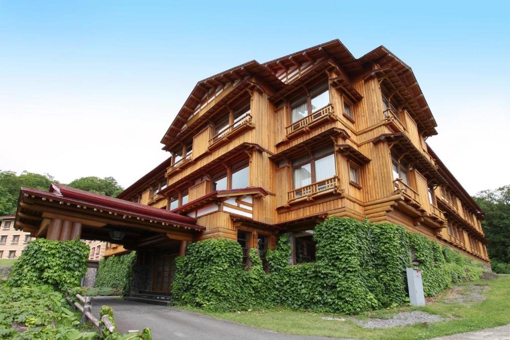 a wooden house with ivy on the side of it at Towada Hotel in Kosaka