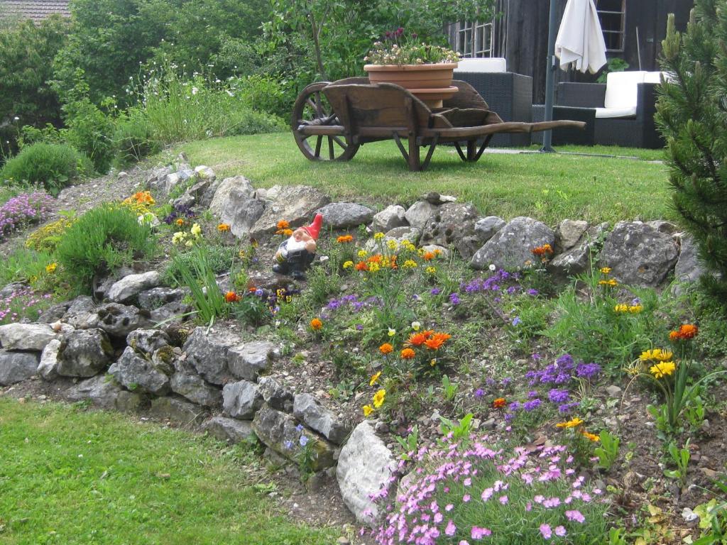 um jardim com flores e um banco no quintal em Bed & Breakfast aux Enges em Enges