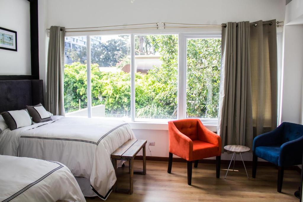 a bedroom with two beds and a window and a chair at Meraki Boutique Hotel in Guatemala