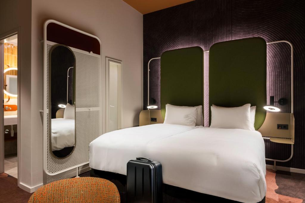 a bedroom with a large white bed and two mirrors at You Hotel Budapest - Handwritten Collection in Budapest