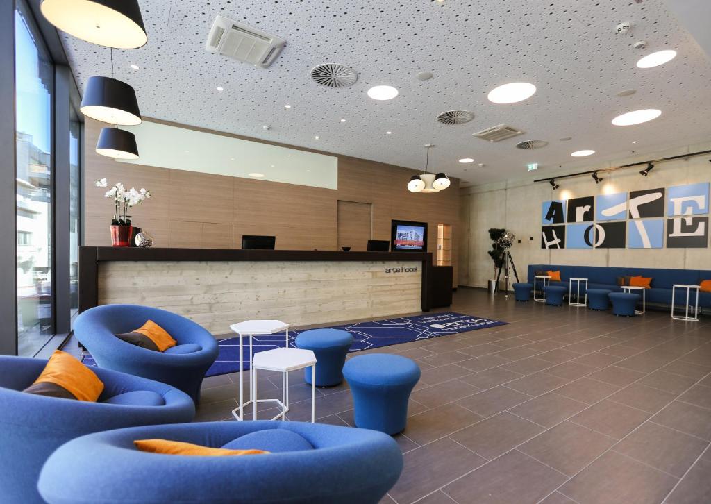 eine Lobby mit blauen Stühlen und einer Theke in einem Gebäude in der Unterkunft arte Hotel Kufstein in Kufstein