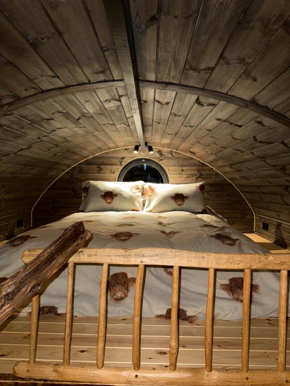 a bed in a room with a wooden ceiling at Luxury Glamping Pods at Pool House Farm 