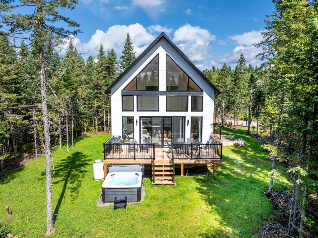 a large white house with a deck and a pool at Spa and Pool Table - Chalet Ayoka in Valcartier Station