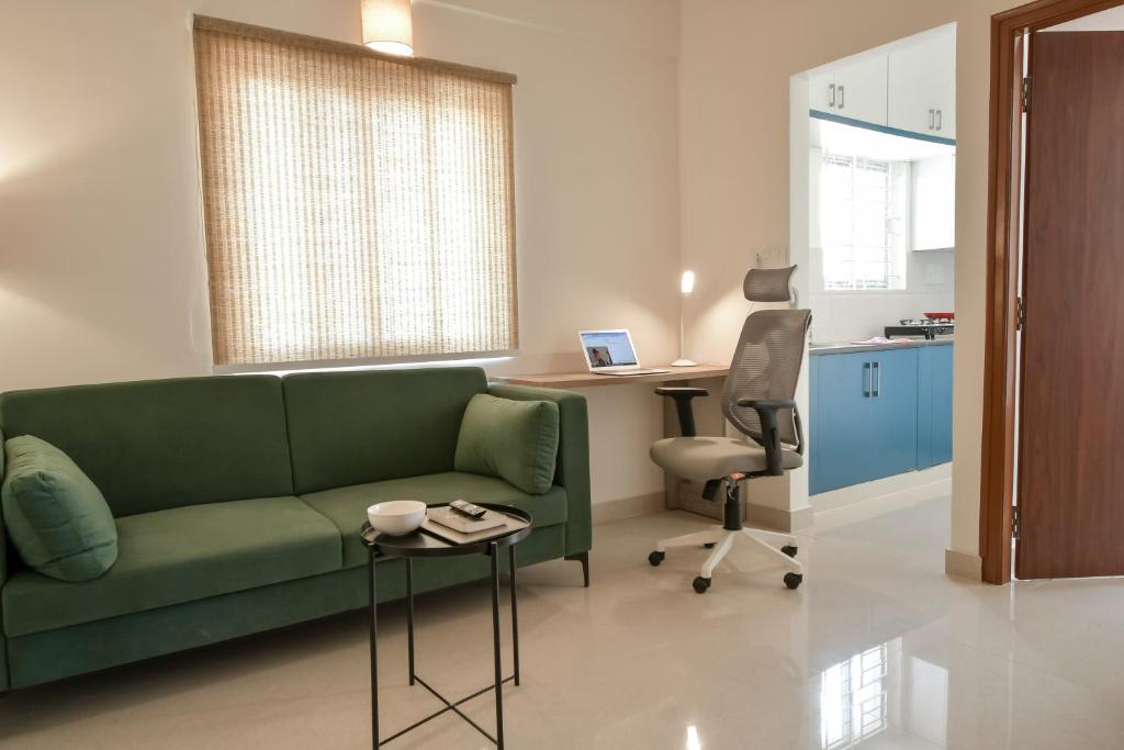 バンガロールにあるHomeSlice Manor, Premium Apartment in Whitefieldの緑のソファとテーブルのあるリビングルーム