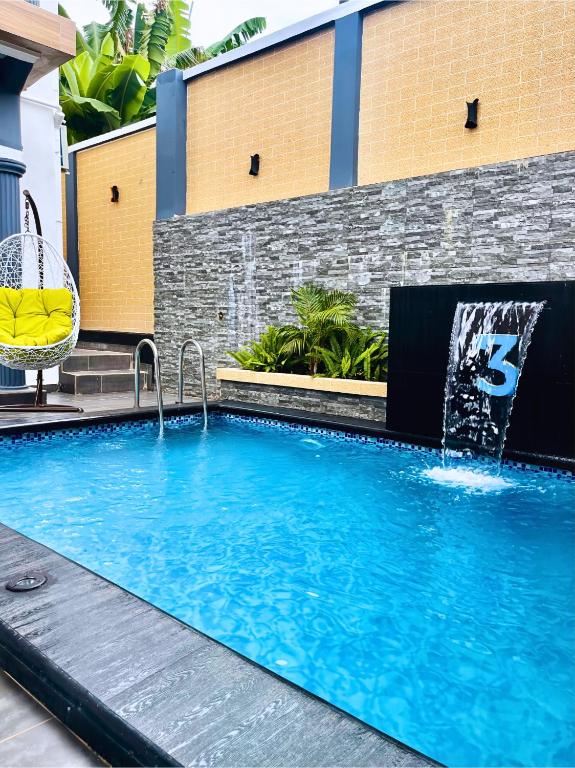 a swimming pool with a water fountain in front of a building at Aj3 LUXURY HOME in Yaoundé