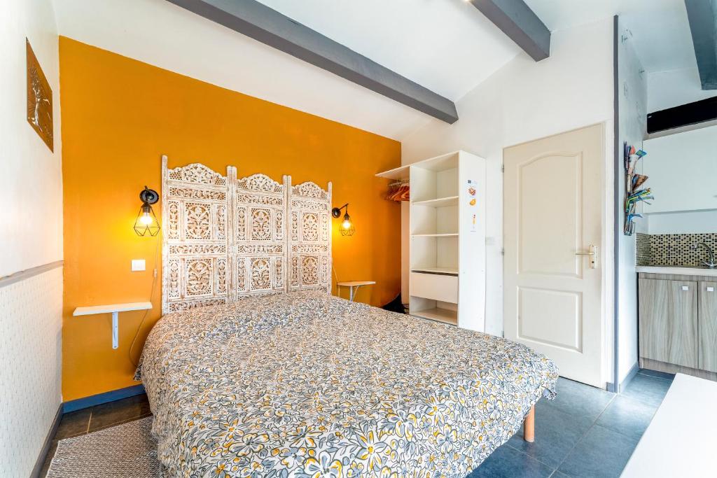 een slaapkamer met een bed met een oranje muur bij Studette Olivier in Les Taillades