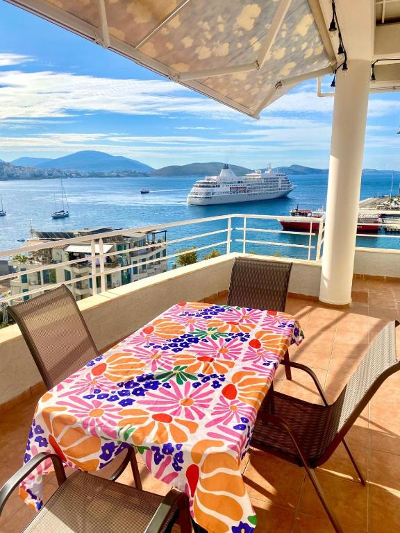 a table and chairs on a balcony with a cruise ship at Sea View Apartment in Sarandë