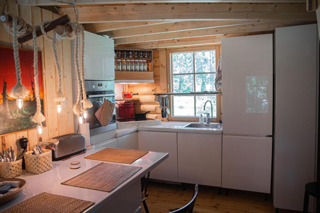 a kitchen with a white refrigerator and a sink at Design Cabin with Jacuzzi, Sauna & Nature in Pertunmaa