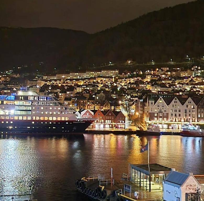 a city at night with a cruise ship in the water at Central, lovely apartment with a unique view in Bergen