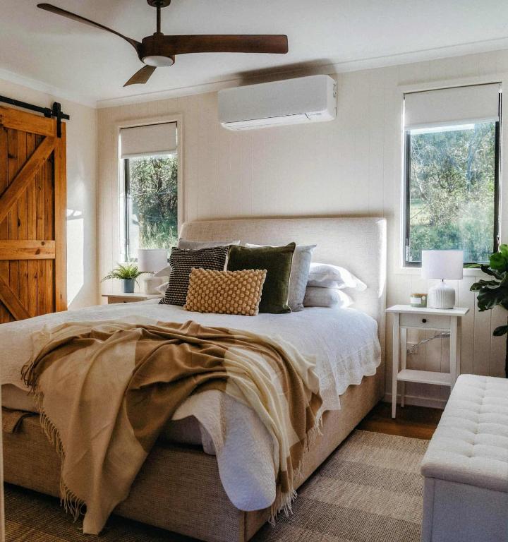 a bedroom with a large bed with a ceiling fan at Gumtop - Luxury Farmhouse Cabin in Bunburra