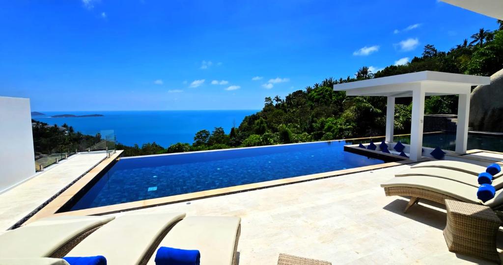 a pool with chairs and the ocean in the background at BLUE ELEPHANT Luxury Pool Villa Koh Samui 6 Bedrooms in Koh Samui 