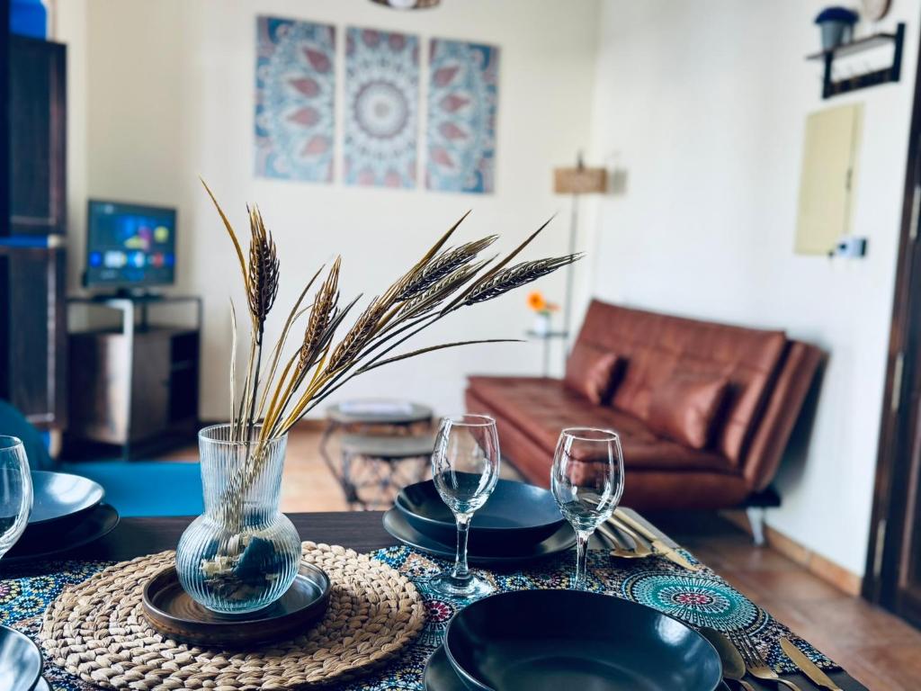 a table with glasses and plates and a vase with grass at Apartamento RÚSTICO ÁRABE en el CORAZÓN de Córdoba in Córdoba
