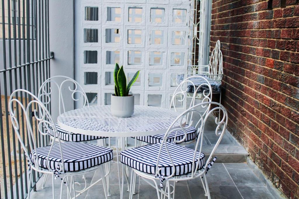 a table and chairs with a potted plant on a patio at Casa Myla, 2 Kuiseb Street, Windhoek in Windhoek