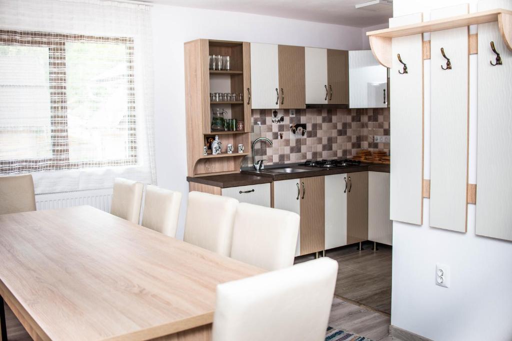 a kitchen with a wooden table and white cabinets at Pensiunea Mateș in Horea