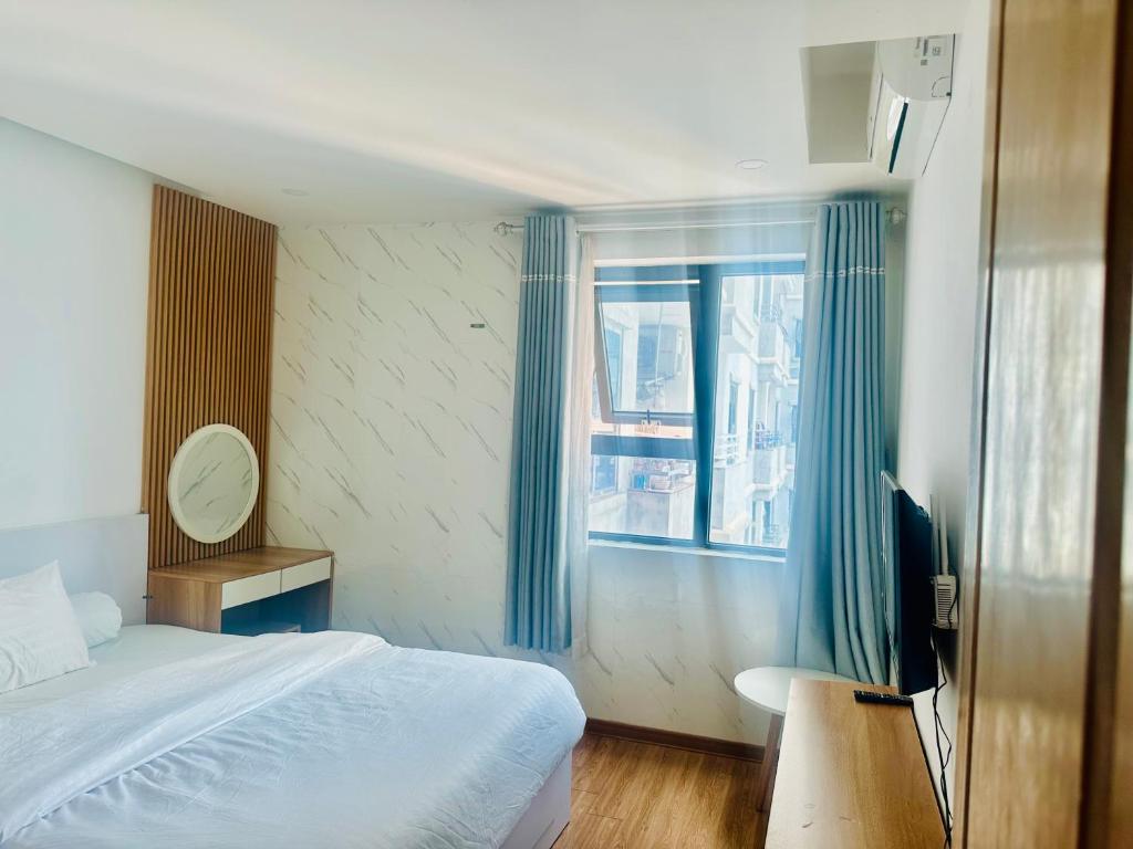 a bedroom with a bed and a television and a window at My Khe Beach-My An Son Tra Da Nang-ANV APT in Da Nang