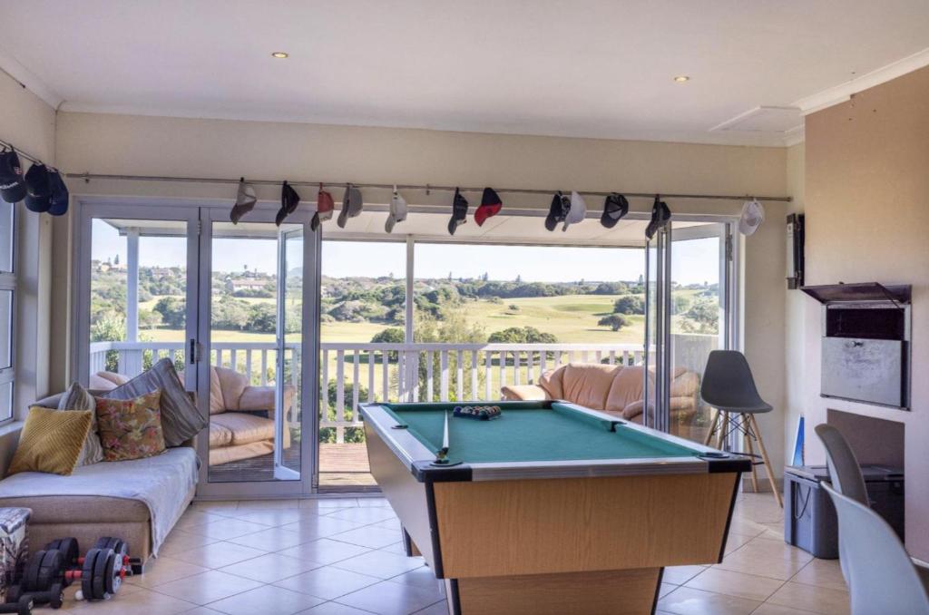 a living room with a pool table and a balcony at The Golf Shack in Port Alfred