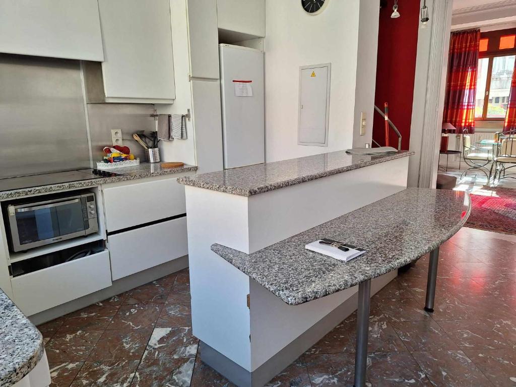 una cucina con mobili bianchi e un piano di lavoro di Charmant Duplex Historique au Cœur de Liège a Liegi