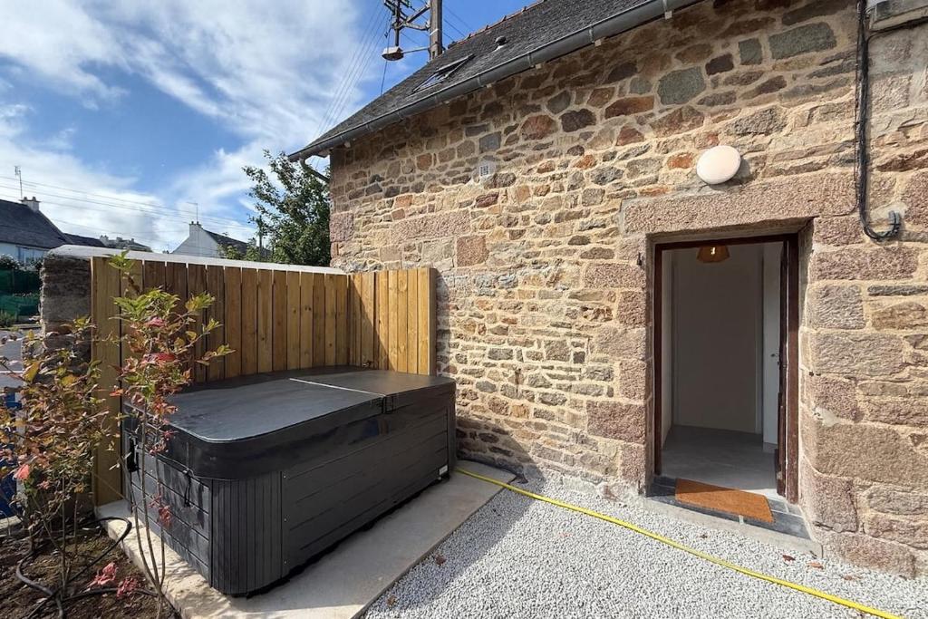 a brick building with a black chest next to a door at Maison refaite à neuf- avec Jacuzzi- LE HOMARD 15 in Perros-Guirec