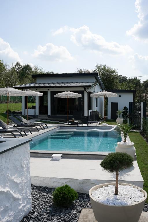 a swimming pool with chairs and umbrellas at Aeri Nature Concept in Baljevac
