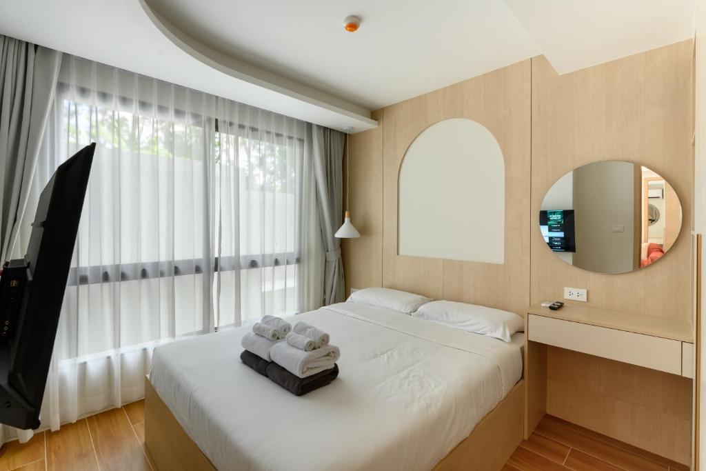 a bedroom with a bed with a mirror and a window at Fantasea Condo Kamala A210 2BDRM by Phuket Sabay Rent in Kamala Beach