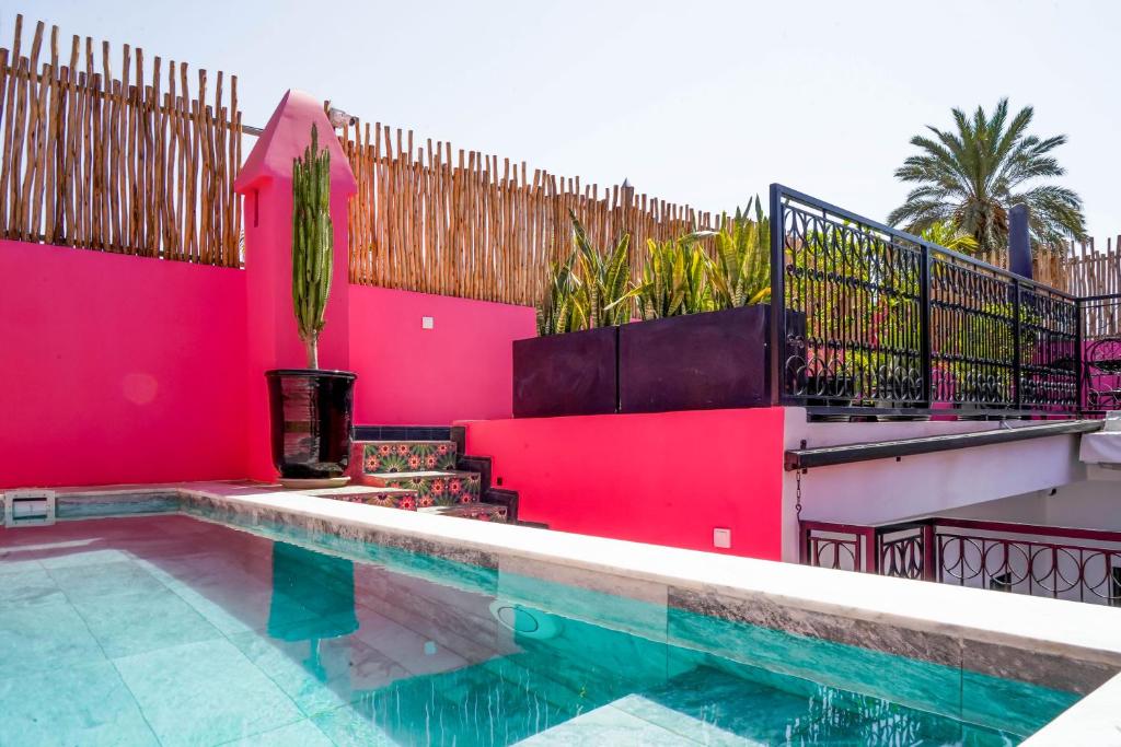 a house with a swimming pool and a red wall at Riad Looma in Marrakesh