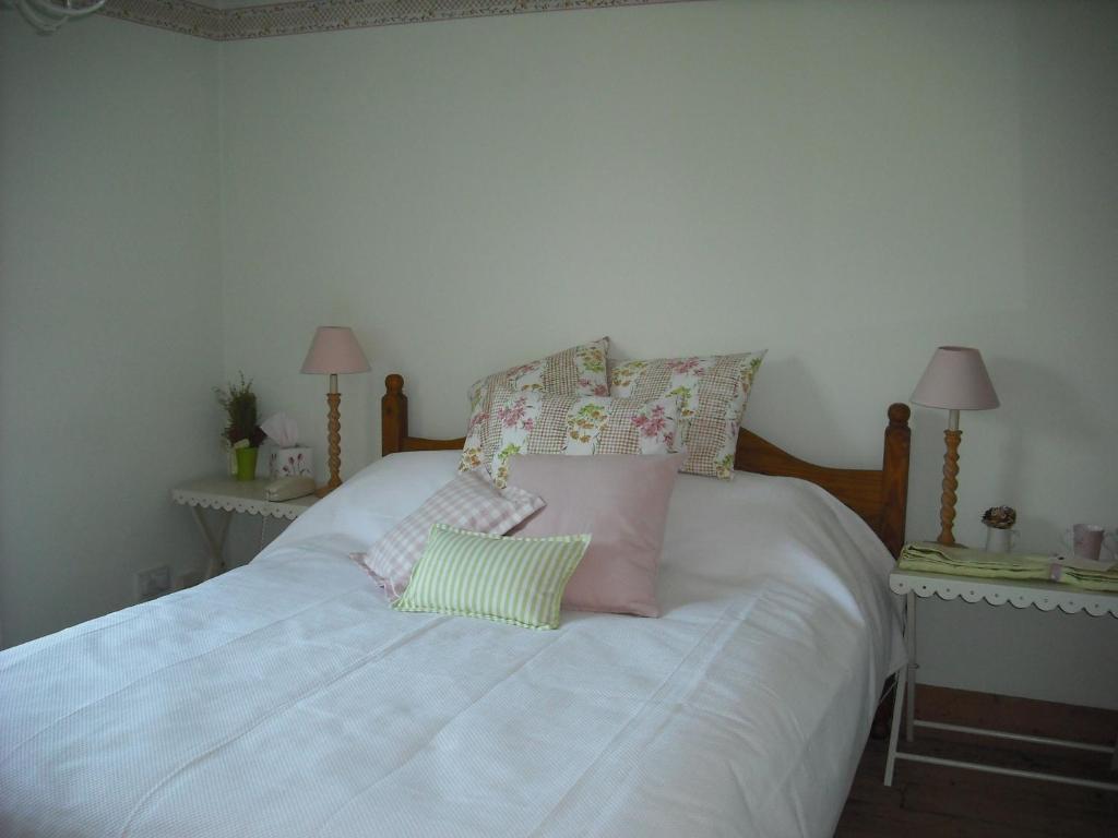 a bedroom with a white bed with pillows on it at Charmantes Cottage im Landhausstil in Kearsney, Dover 