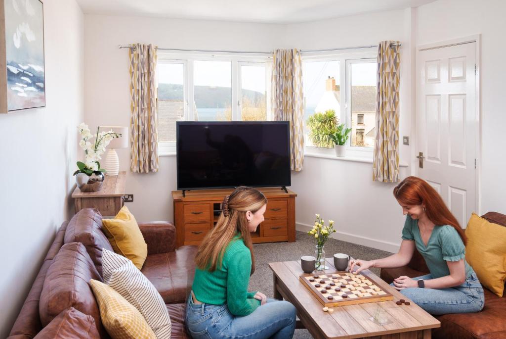 two girls playing chess in a living room at Gwbert Holiday Cottages, Riversmouth in Gwbert