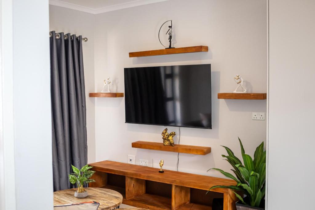 a living room with a television and a wooden bench at The Dawn in Gaborone