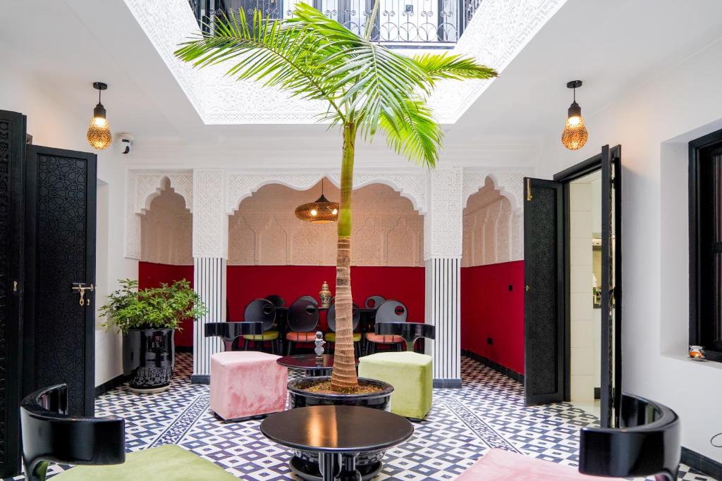 a palm tree in a room with a table and chairs at Riad Looma in Marrakech