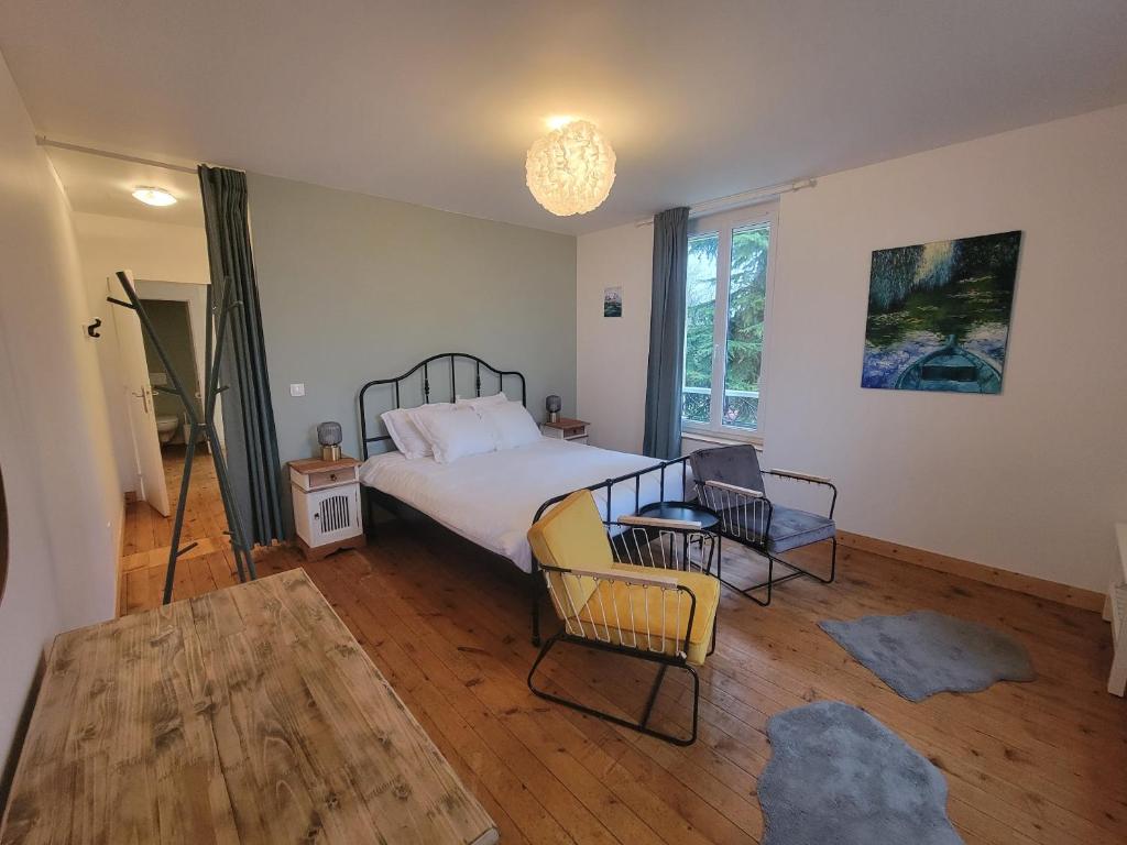 a bedroom with a bed and a table and chairs at La Sucrerie - chambres à la campagne in Fontenay