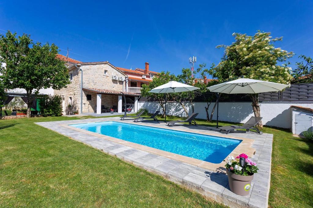 - une piscine dans une cour avec 2 parasols dans l'établissement Stone House Furlani, à Svetvinčenat