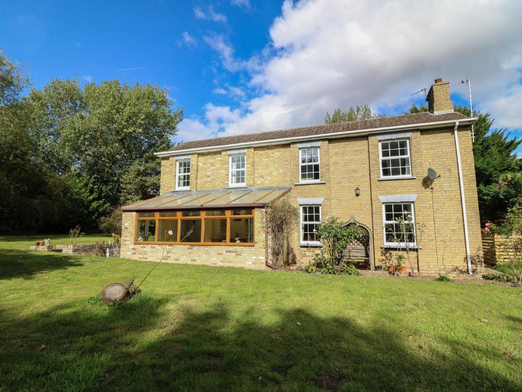 a large brick house on a grass field at Larkspur Cottage in Alford